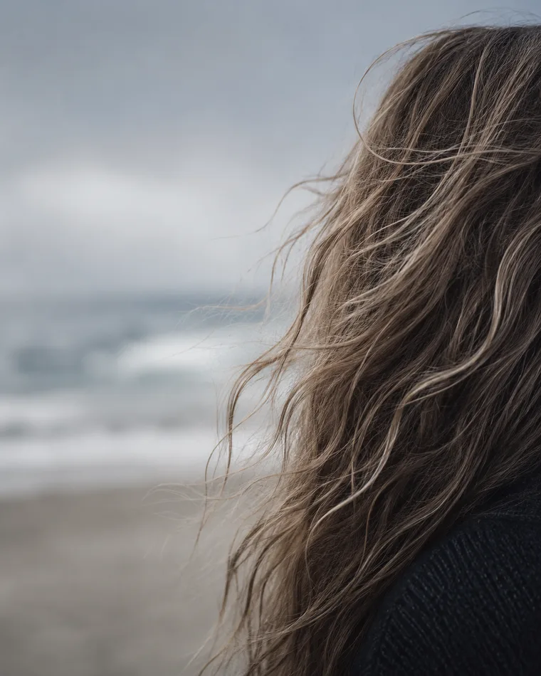 Windswept, naturally textured long hair against an overcast coast